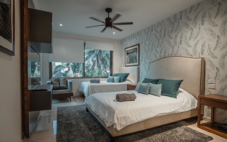 A stylish guest suite at Villa Patrón featuring two double beds, soft lighting, and tropical-inspired decor — comfort and elegance in every detail. | Suite de huéspedes en Villa Patrón con dos camas matrimoniales, iluminación suave y decoración inspirada en la naturaleza tropical — confort y elegancia en cada detalle.
