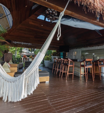 The palapa lounge at Villa Patrón offers a relaxed Caribbean atmosphere with a bar, lounge seating, and a hammock overlooking the lagoon. | La palapa lounge de Villa Patrón ofrece un ambiente caribeño relajado con bar, asientos tipo lounge y una hamaca con vista a la laguna.
