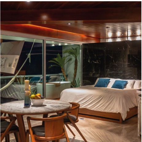 Elegant and serene — Villa Quarry’s bedroom blends marble textures, warm lighting, and ocean views for an intimate Caribbean retreat. | Elegante y sereno — el dormitorio de Villa Quarry combina mármol, luz cálida y vista al mar para una escapada caribeña íntima.
