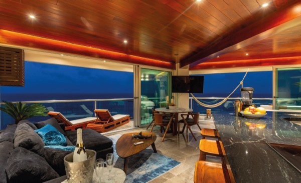 Luxury oceanfront living room at Villa Quarry Cancun with panoramic sea view, hammock, and modern wood ceiling | I Live Where You Vacation / Sala frente al mar en Villa Quarry Cancún con vista panorámica, hamaca y techo de madera moderna | I Live Where You Vacation