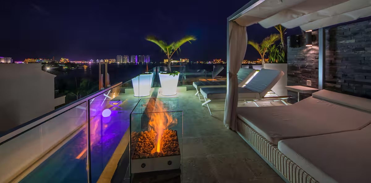 Enjoy the best sunset views from Villa Patrón Cancun’s private rooftop lounge, featuring a lap pool, fire pit, and elegant daybeds overlooking the Nichupté Lagoon. | Disfruta de los mejores atardeceres desde el rooftop privado de Villa Patrón Cancún, con alberca tipo lap pool, fogata y camas de día con vista a la Laguna Nichupté.
