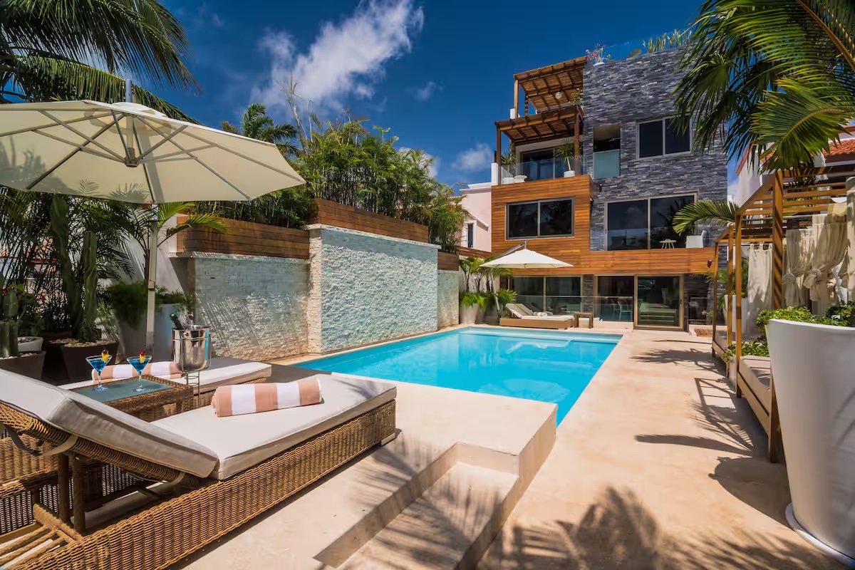 The outdoor pool area at Villa Patrón features sun loungers, shaded daybeds, and tropical surroundings — a perfect spot to relax and enjoy the Cancún sun. | La zona exterior de Villa Patrón ofrece camastros, camas de día y vegetación tropical — el lugar perfecto para disfrutar el sol de Cancún.
