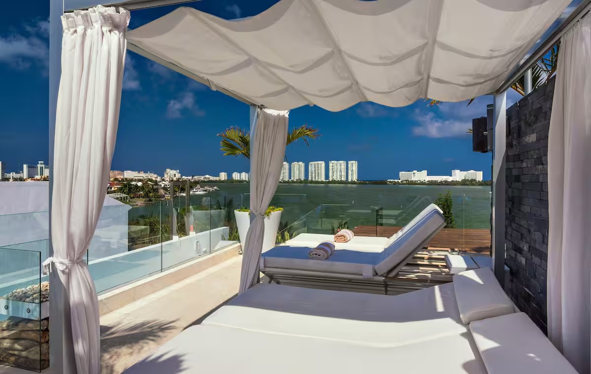 The rooftop terrace at Villa Patrón offers a serene escape with sweeping lagoon views, elegant loungers, and a luxurious lap pool under the Caribbean sky. | La terraza en la azotea de Villa Patrón ofrece un refugio sereno con vistas panorámicas a la laguna, camastros elegantes y una alberca tipo lap bajo el cielo caribeño.

