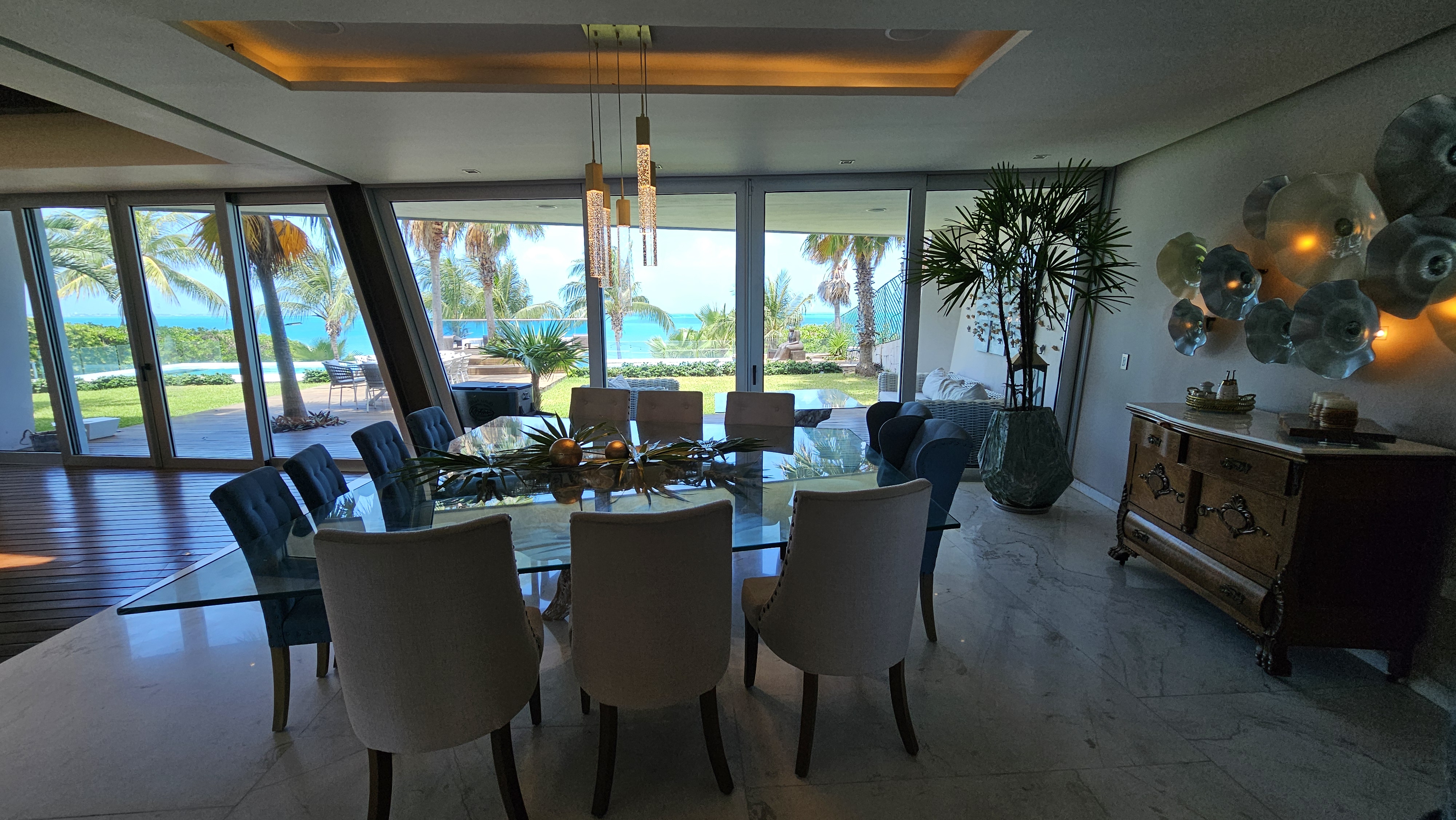 Elegant glass dining table with ocean view and tropical design — ideal for fine dining experiences in Cancun. | Mesa de comedor elegante con vista al mar y diseño tropical — ideal para experiencias gastronómicas de lujo en Cancún.
