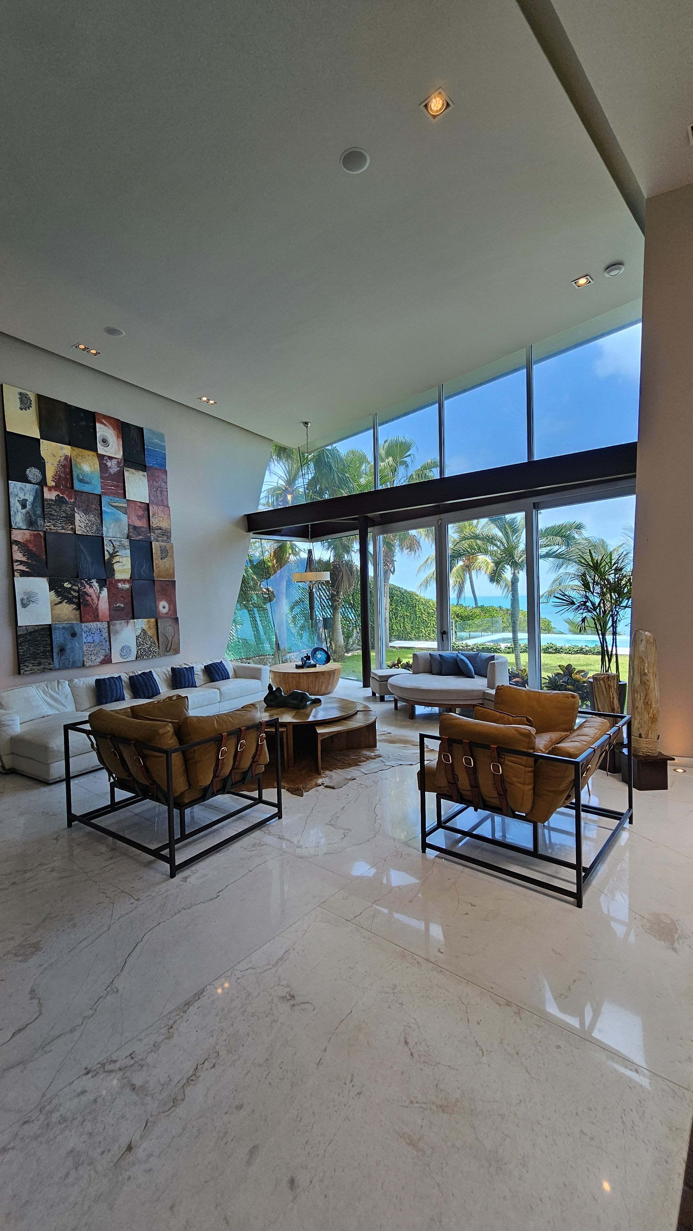 Contemporary living room with ocean views, art wall and natural light — ideal for luxury vacations in Cancun. | Sala contemporánea con vista al mar, muro artístico y luz natural — ideal para vacaciones de lujo en Cancún.
