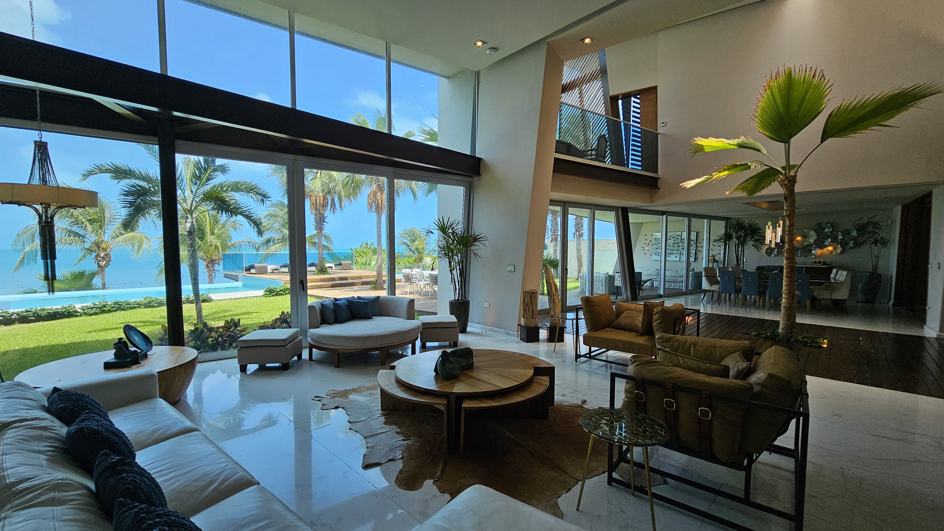 Stylish open-plan living area with marble floors, designer bar and ocean views — perfect for luxury gatherings in Cancun. | Área social moderna con pisos de mármol, barra de diseño y vista al mar — perfecta para reuniones de lujo en Cancún.
