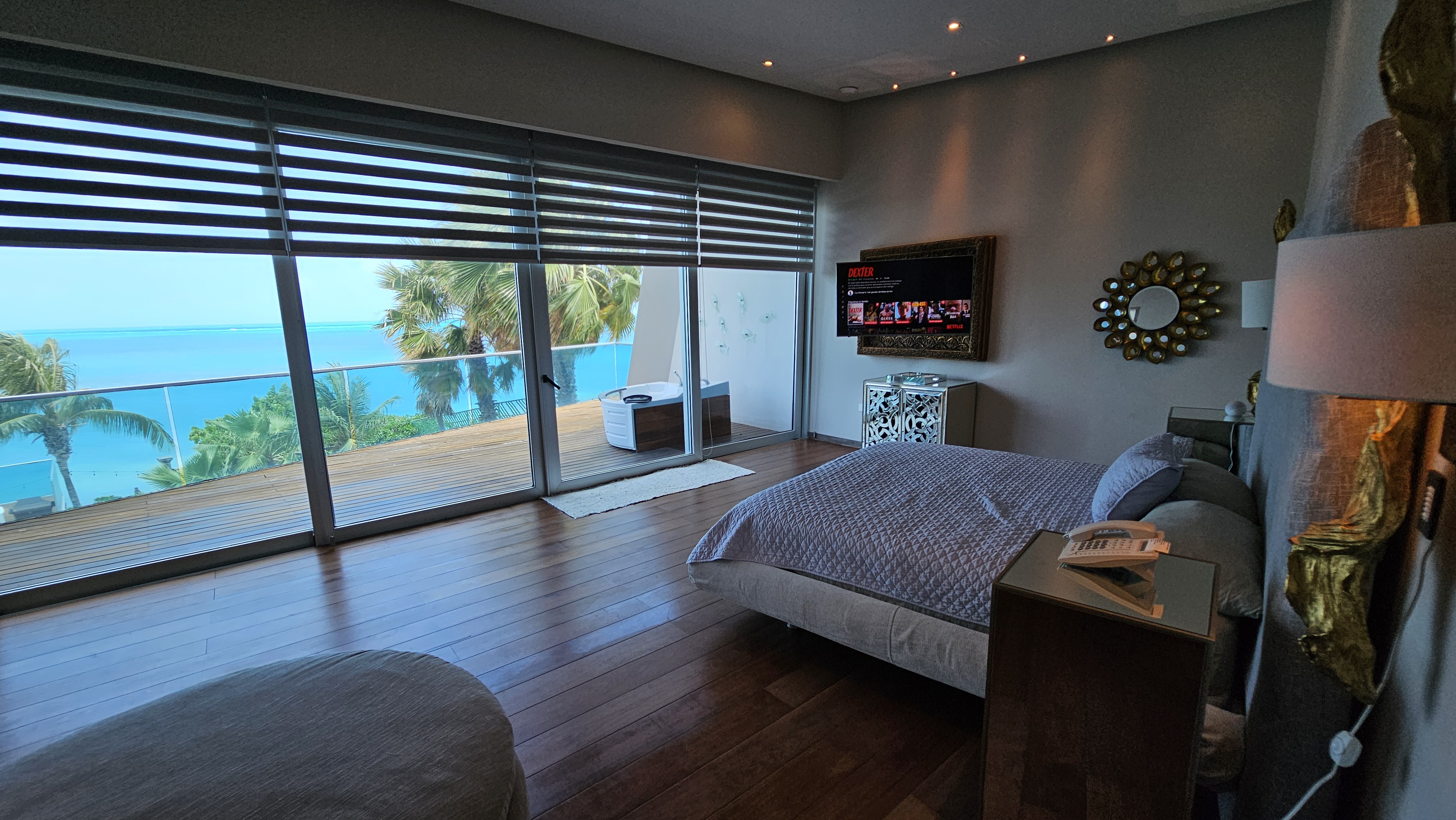 Master bedroom with ocean view terrace, jacuzzi and hardwood floors — ideal for luxury stays in Cancun. | Recámara principal con terraza frente al mar, jacuzzi y pisos de madera — ideal para estancias de lujo en Cancún.
