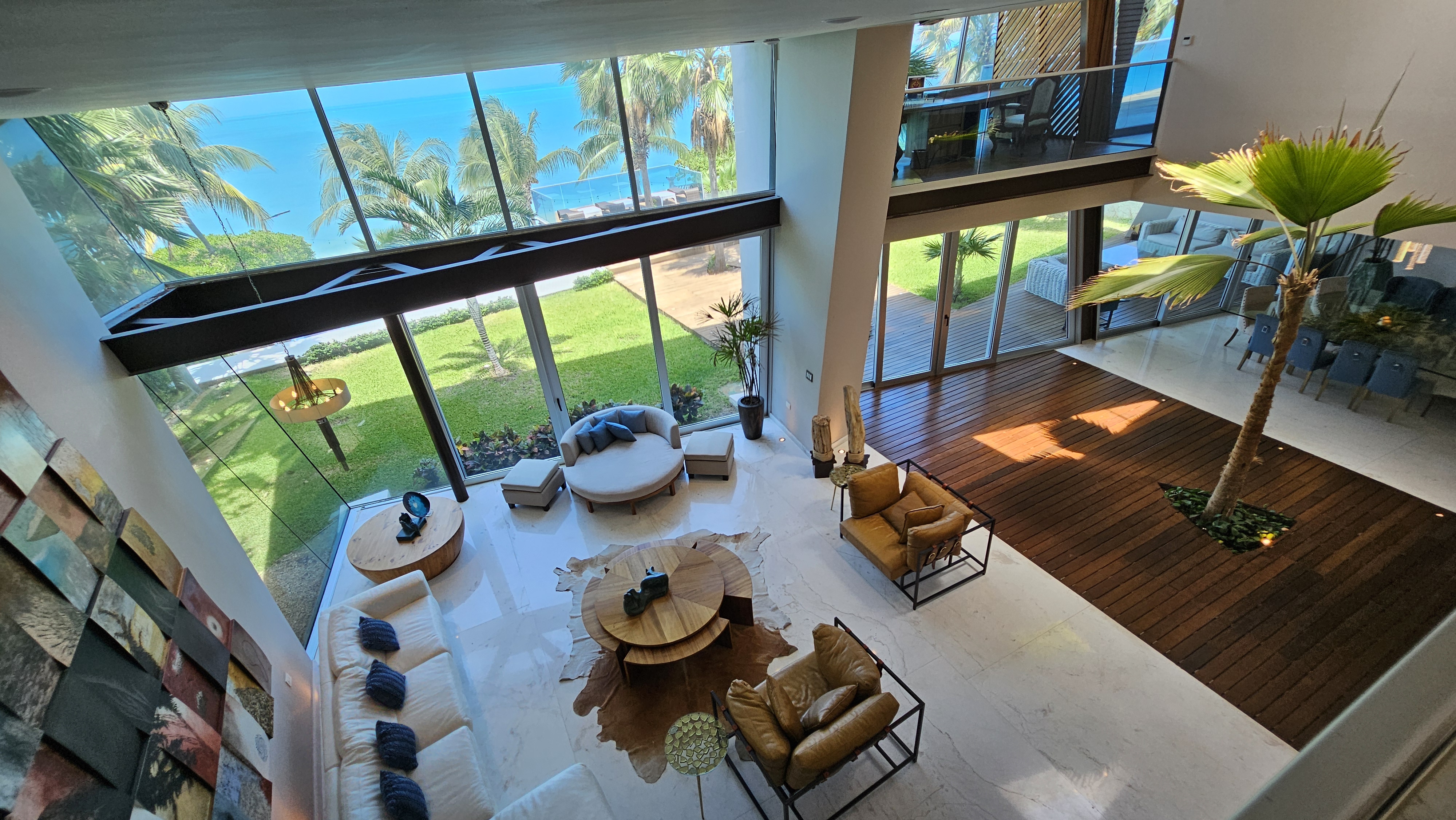 Panoramic ocean-view living room with double-height ceiling, marble floors and private deck — ideal for luxury stays in Cancun. | Sala con vista al mar, doble altura, pisos de mármol y deck privado — ideal para estancias de lujo en Cancún.