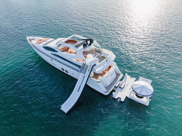 Aerial view of luxury yacht Truco VII 85 ft with inflatable slide and floating lounge in the Caribbean Sea – I Live Where You Vacation | Vista aérea del yate de lujo Truco VII de 85 pies con tobogán inflable y plataforma flotante en el mar Caribe – I Live Where You Vacation
