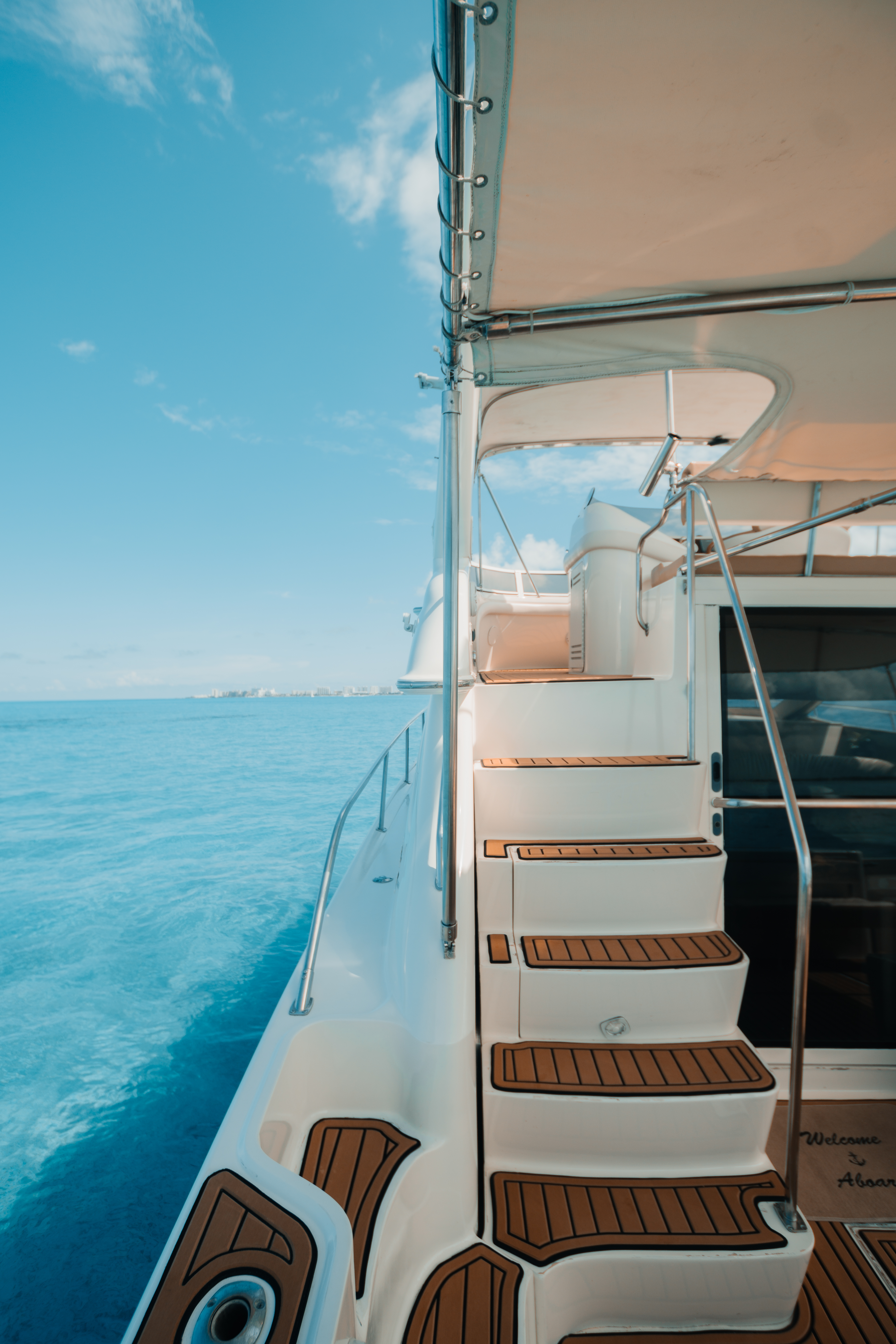 Elegant teak steps lead to the Sea Daddy’s flybridge, where open-air views meet luxury comfort. | Escalones de teca conducen al flybridge del Sea Daddy, donde las vistas abiertas se combinan con el confort de lujo.
