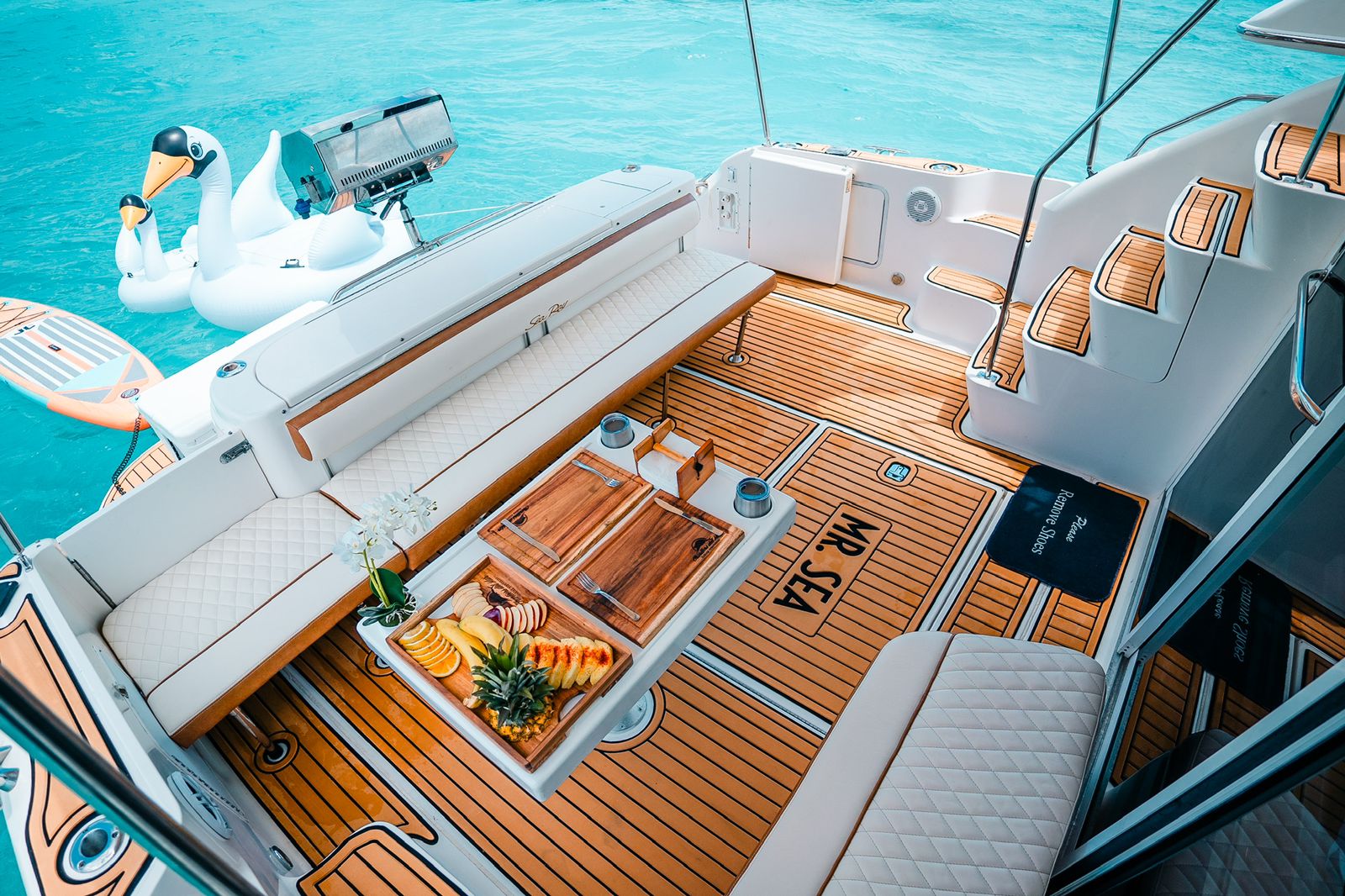 Relax on the teak deck of the 50 ft Sea Ray “Mr Sea,” featuring a dining table, fruit platter, and stunning Caribbean views. | Relájate en la cubierta de teca del Sea Ray “Mr Sea” de 50 pies, con mesa de comedor, bandeja de frutas y vistas espectaculares del Caribe.
