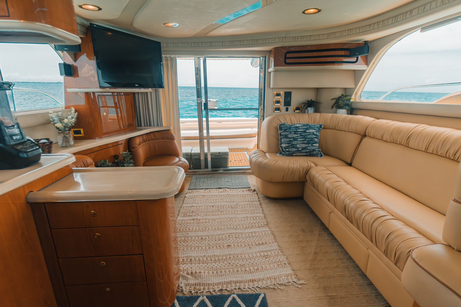 Spacious and bright, the interior salon of the 52 ft Sea Ray “Sea Mami” features plush leather seating, panoramic windows, and a relaxing ocean backdrop. | Amplio y luminoso, el salón interior del Sea Ray “Sea Mami” de 52 pies cuenta con cómodos asientos de piel, ventanales panorámicos y una relajante vista al mar.
