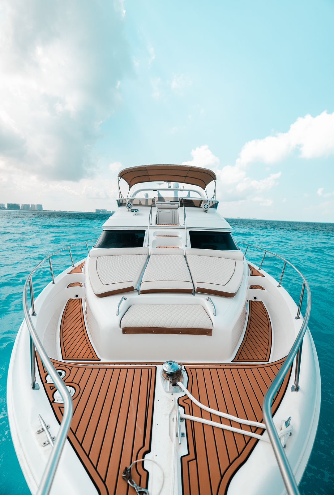 Spacious bow deck with elegant sun loungers and turquoise Caribbean waters ahead. | Amplia proa con elegantes camastros y aguas turquesa del Caribe al frente.
