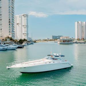 Sea Ray 55 ft Sin Nombre yacht cruising in the marina of Cancún with modern skyline in the background – I Live Where You Vacation | Yate Sea Ray 55 pies Sin Nombre navegando en la marina de Cancún con el moderno horizonte al fondo – I Live Where You Vacation