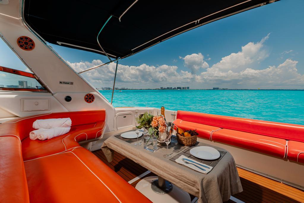 A refined dining setup aboard the Sin Nombre 55 ft Sea Ray yacht — the perfect setting for a romantic escape in Cancún. | Una elegante mesa a bordo del yate Sin Nombre 55 ft Sea Ray — el escenario perfecto para una escapada romántica en Cancún.
