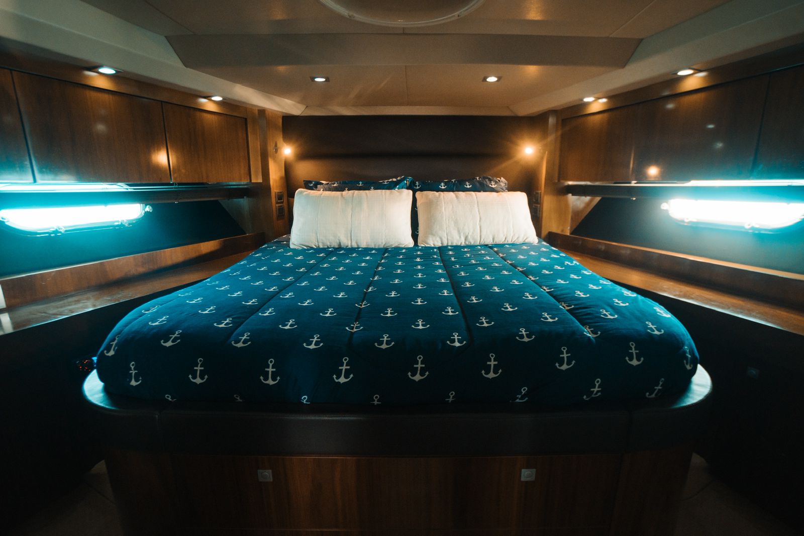 The master suite aboard the Tatabu offers refined elegance and comfort, featuring premium wood finishes, warm lighting, and a queen-size bed with nautical accents. | La suite principal del Tatabu ofrece elegancia y confort, con acabados de madera, iluminación cálida y una cama tamaño queen con detalles náuticos.
