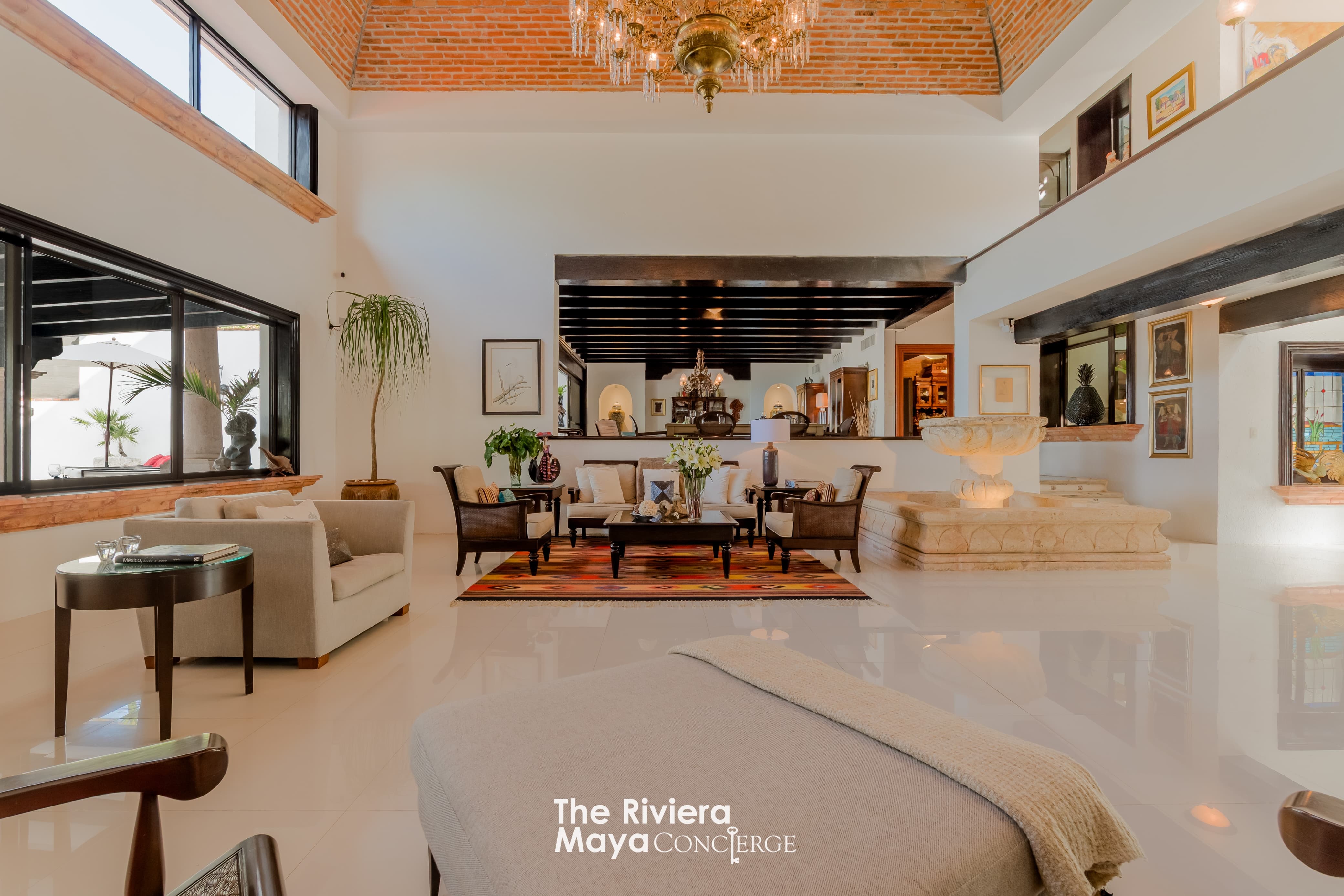 Elegant living room featuring vaulted ceilings, chandelier, and indoor fountain — Villa Albatros, part of I Live Where You Vacation’s Riviera Maya luxury villa collection. | Elegante sala con techos abovedados, candelabro y fuente interior — Villa Albatros, parte de la colección de lujo Riviera Maya de I Live Where You Vacation.

