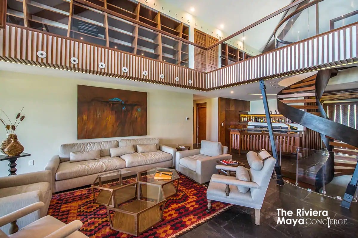 The contemporary living area at Villa Gulf features a custom spiral staircase, stylish lounge, and private bar — a refined space for relaxation and gatherings by I Live Where You Vacation. | La sala contemporánea de Villa Gulf presenta una escalera de caracol personalizada, un salón elegante y bar privado — un espacio refinado para relajarse y convivir con I Live Where You Vacation.
