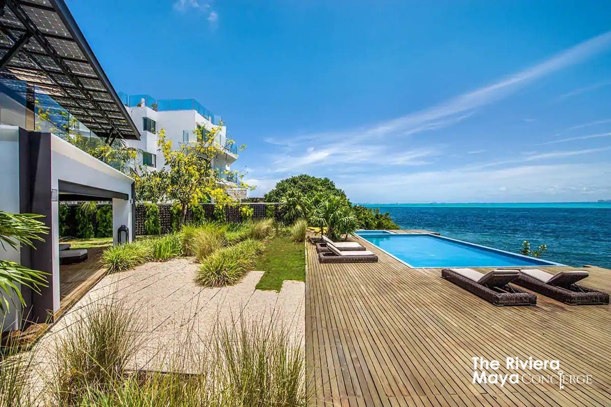 Villa Gulf’s oceanfront terrace features an elegant infinity pool, sun loungers, and lush gardens overlooking the Caribbean — pure island serenity curated by I Live Where You Vacation. | La terraza frente al mar de Villa Gulf ofrece una elegante alberca infinita, camastros y jardines exuberantes con vista al Caribe — pura serenidad isleña curada por I Live Where You Vacation.

