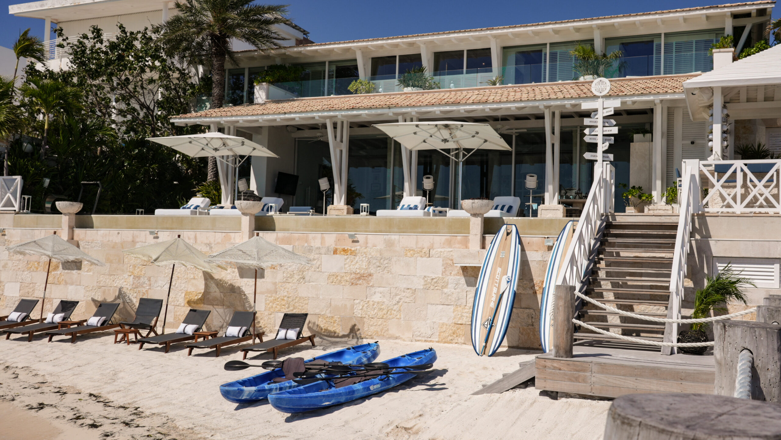 Relax by the sea at Villa Sha’s private beachfront terrace, featuring kayaks, paddleboards, and shaded lounges for the ultimate Caribbean escape — curated by I Live Where You Vacation. | Relájate junto al mar en la terraza privada frente a la playa de Villa Sha, con kayaks, tablas de paddle y camastros con sombra para una escapada caribeña perfecta — una experiencia curada por I Live Where You Vacation.
