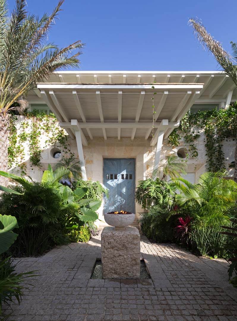 The tropical garden entrance of Villa Sha welcomes guests with lush greenery, natural stone, and modern coastal elegance — curated by I Live Where You Vacation. | La entrada con jardín tropical de Villa Sha recibe a los huéspedes con vegetación exuberante, piedra natural y elegancia costera moderna — una experiencia curada por I Live Where You Vacation.
