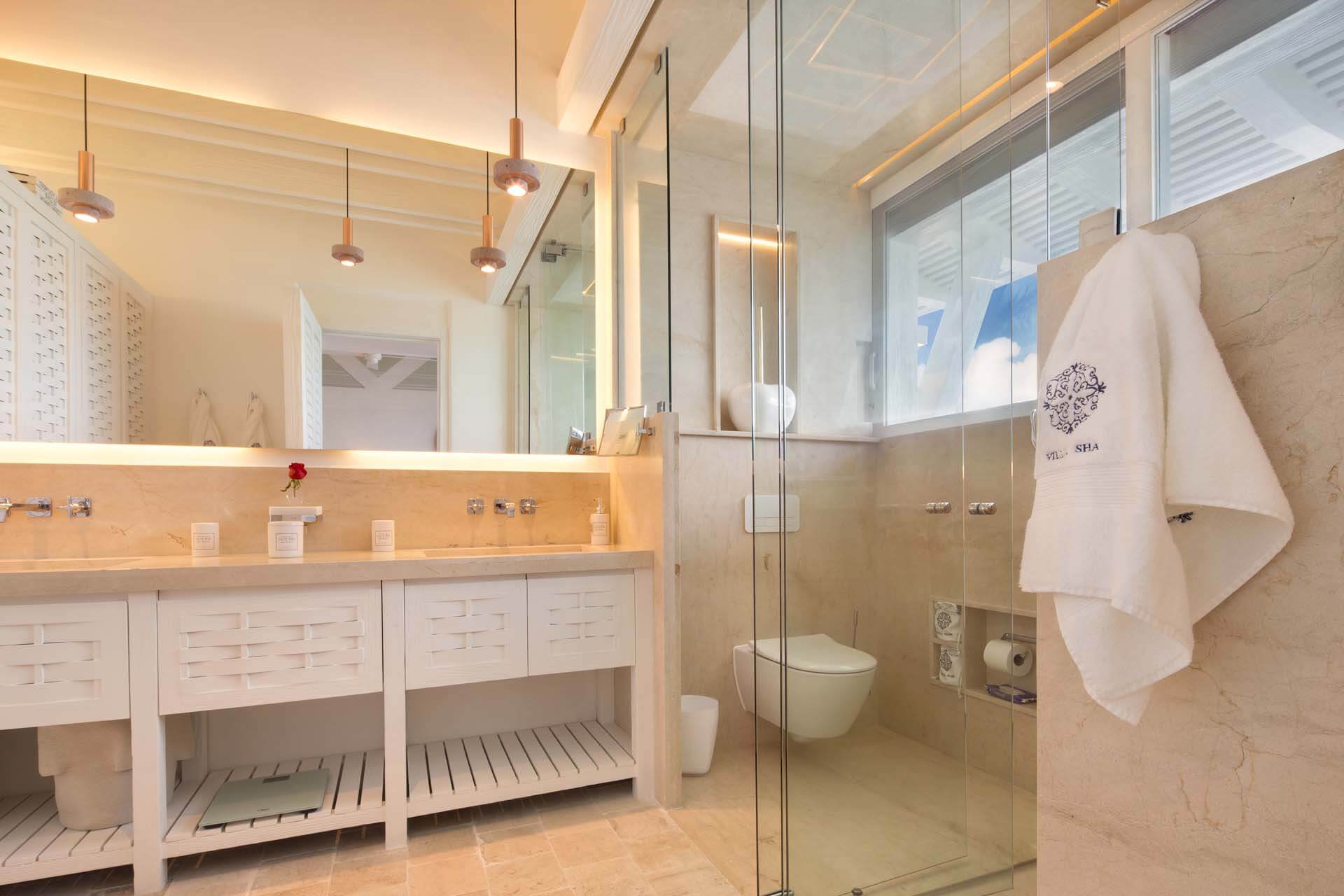 Sophisticated ensuite bathroom with natural light and spa-inspired design. | Baño privado sofisticado con luz natural y diseño inspirado en un spa.
