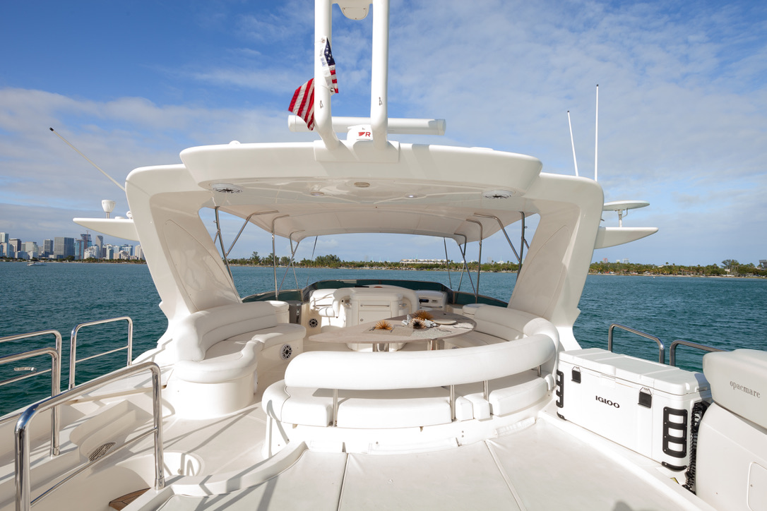 Flybridge deck of the Azimut 80 featuring a shaded lounge, dining table, and breathtaking ocean views, curated by I Live Where You Vacation. | Cubierta flybridge del Azimut 80 con lounge sombreado, mesa de comedor y vistas espectaculares al mar, presentada por I Live Where You Vacation.
