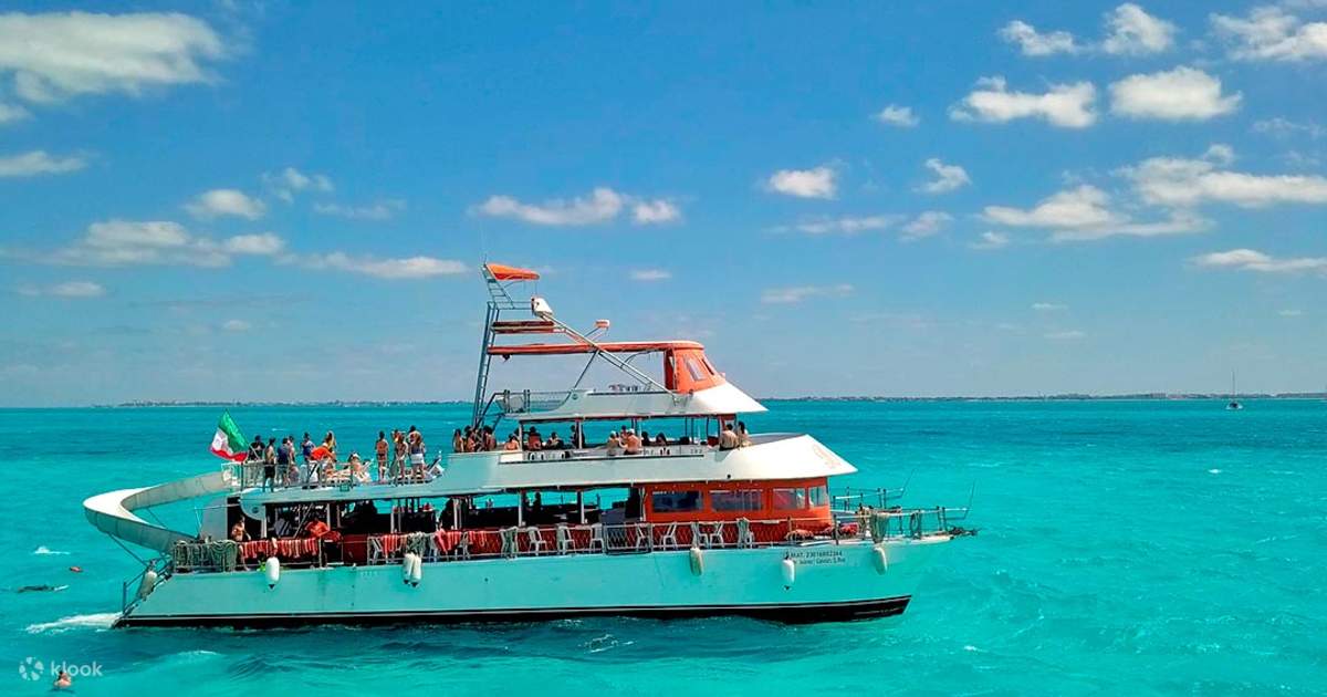 Dancer Cruise Cancun sails across turquoise Caribbean waters with guests enjoying the open deck atmosphere. / Dancer Cruise Cancún navega sobre aguas turquesa del Caribe con invitados disfrutando el ambiente en cubierta.