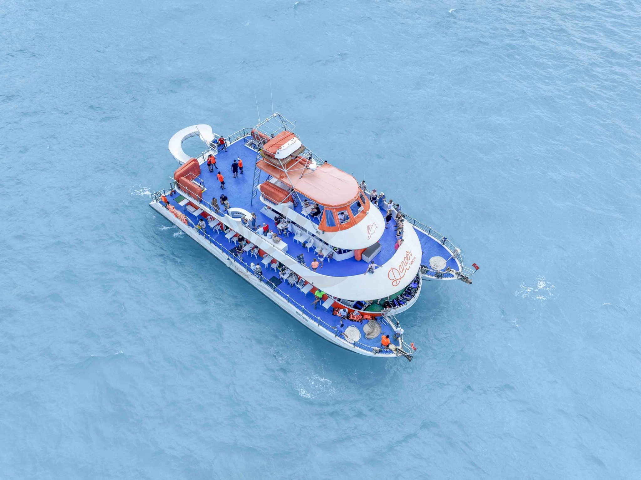 An aerial view of Dancer Cruise Cancun shows its spacious party boat layout over clear Caribbean waters. / La vista aérea del Dancer Cruise Cancún muestra su amplia distribución de barco fiesta sobre aguas cristalinas del Caribe.