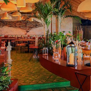 Elegant waterfront dining at Fred’s Cancun by the lagoon, golden sunset light reflecting on calm turquoise waters, gourmet dishes served on polished tables with soft ambient lighting – I Live Where You Vacation | Cena elegante frente a la laguna en Fred’s Cancún, con la luz dorada del atardecer reflejándose sobre aguas turquesa y platos gourmet servidos en mesas pulidas bajo una iluminación ambiental suave – I Live Where You Vacation