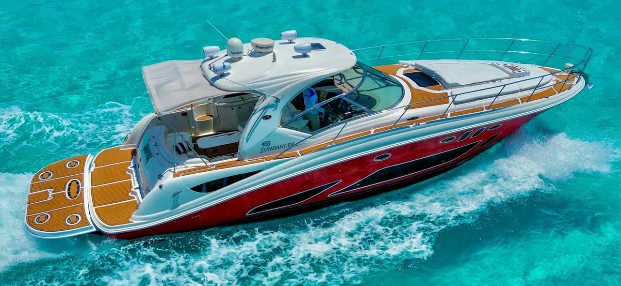 Aerial cruising view of the Red Fire 45ft yacht showing its swim platform and red hull over turquoise water — Vista aérea del yate Red Fire 45ft navegando con plataforma de baño y casco rojo sobre agua turquesa.