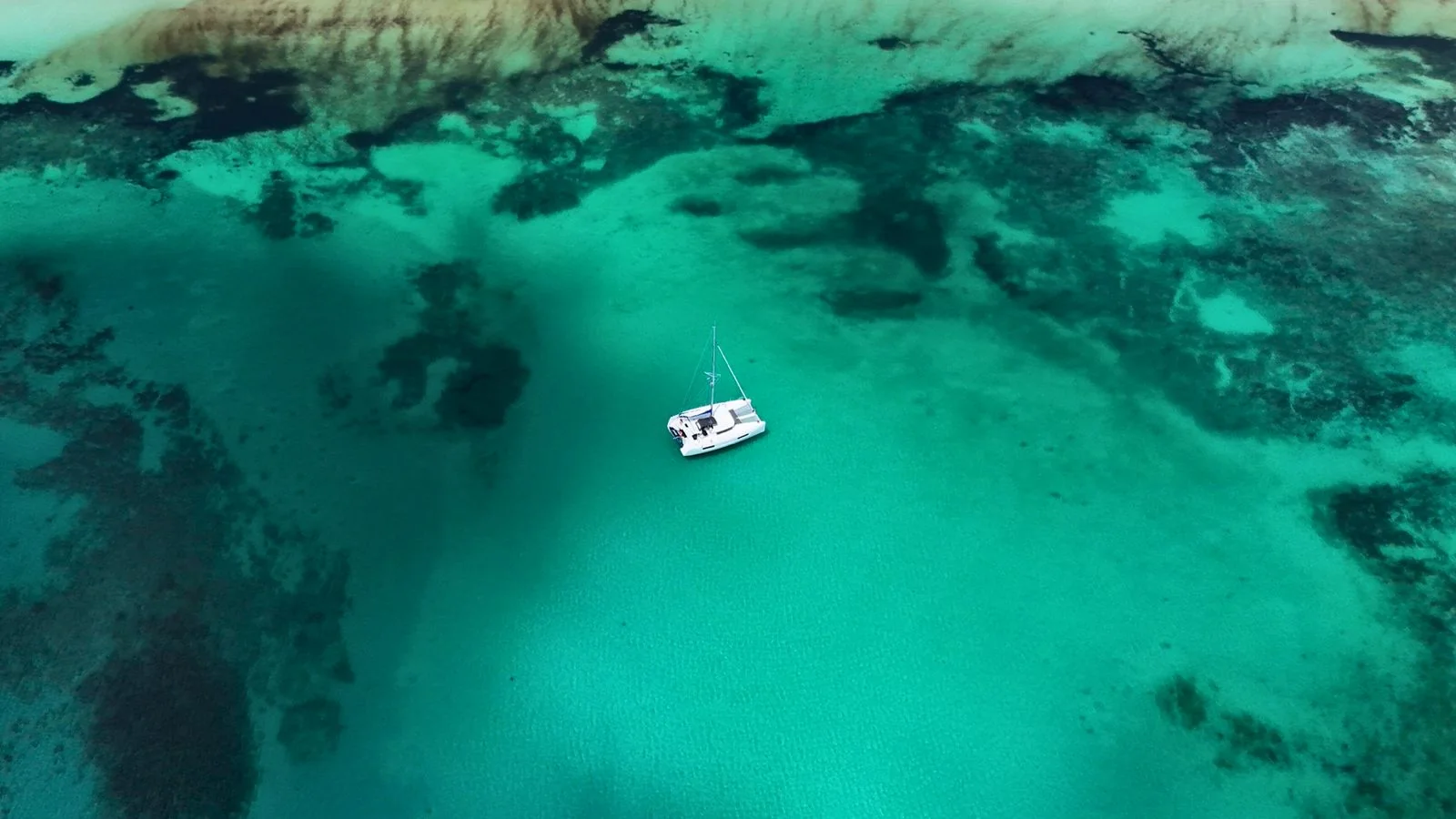 Aerial view of Blue Iris 40ft Lagoon Catamaran over shallow Caribbean water.