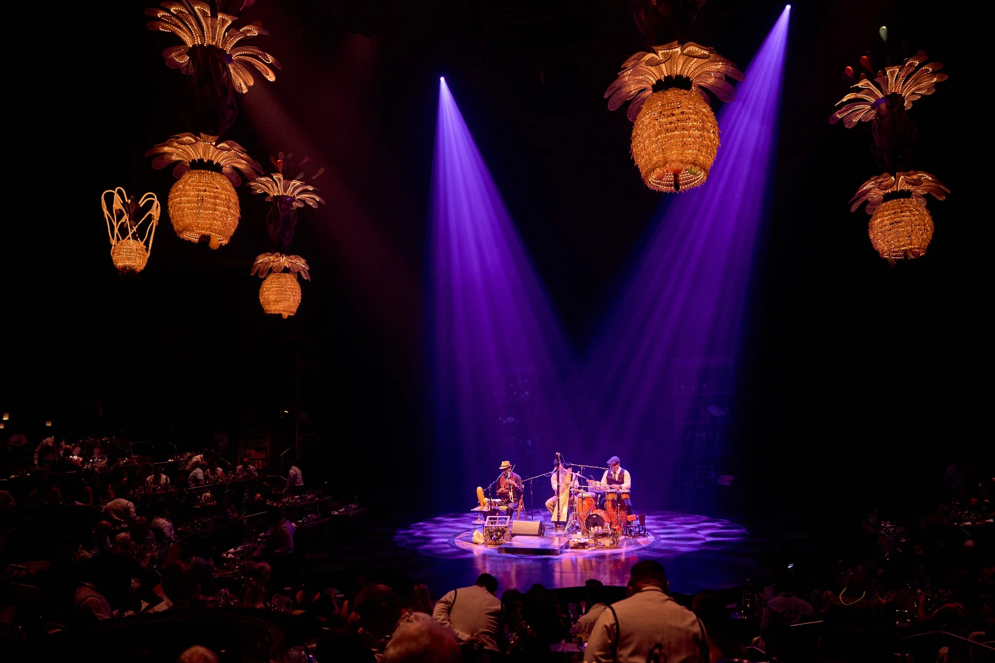 JOYÀ live pre-show musicians beneath illuminated theatre chandeliers